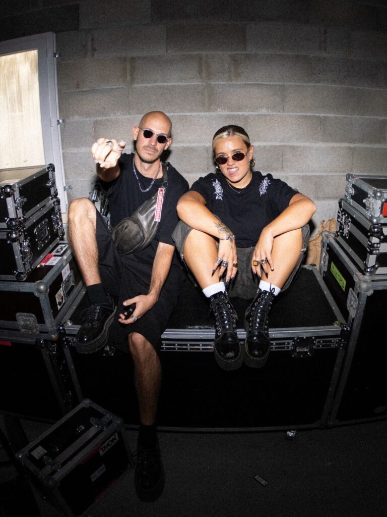 Baptiste et Tara de Jive Me assis sur un flight case en coulisses, Baptiste pointe du doigt