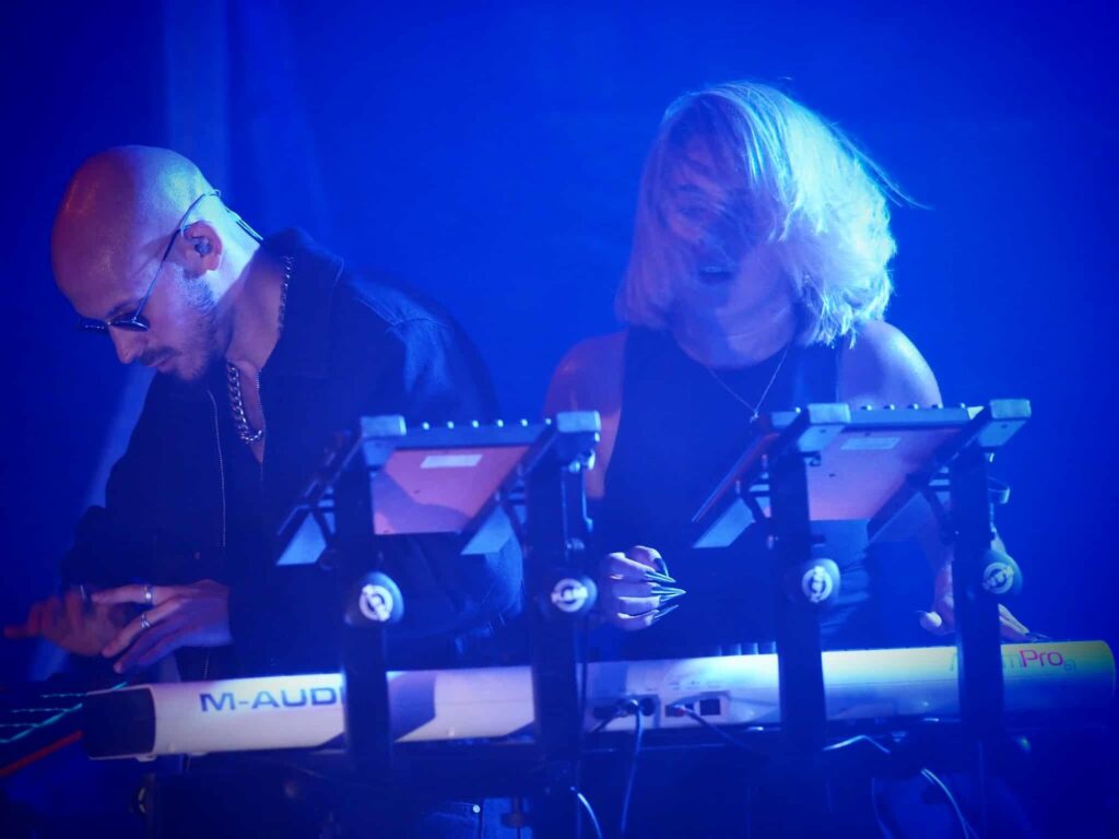 Baptiste et Tara de Jive Me derrière leurs claviers en concert, lumière bleue