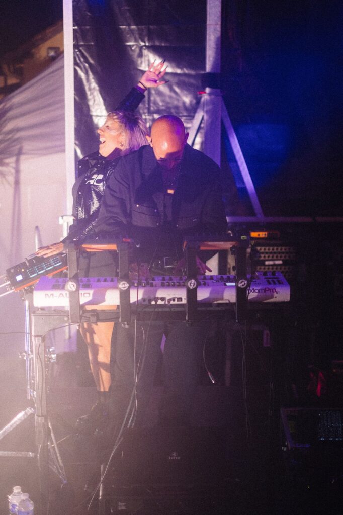 Baptiste aux claviers et synthétiseurs et Tara qui danse sur scène lors d'un concert de festival