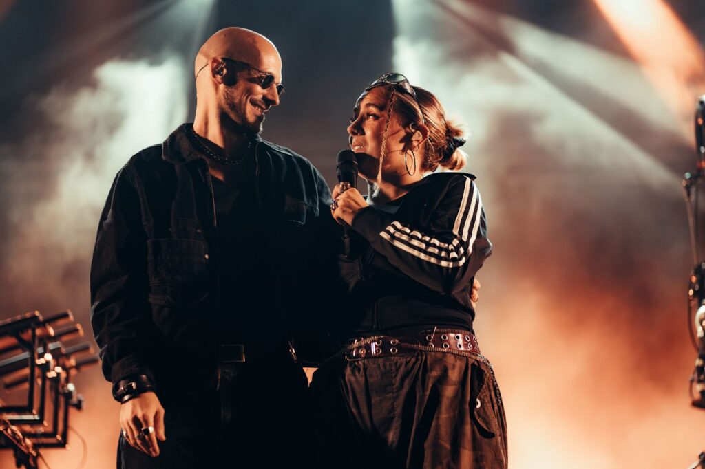 Baptiste et Tara de Jive Me en concert sous les projecteurs et la fumée orange
