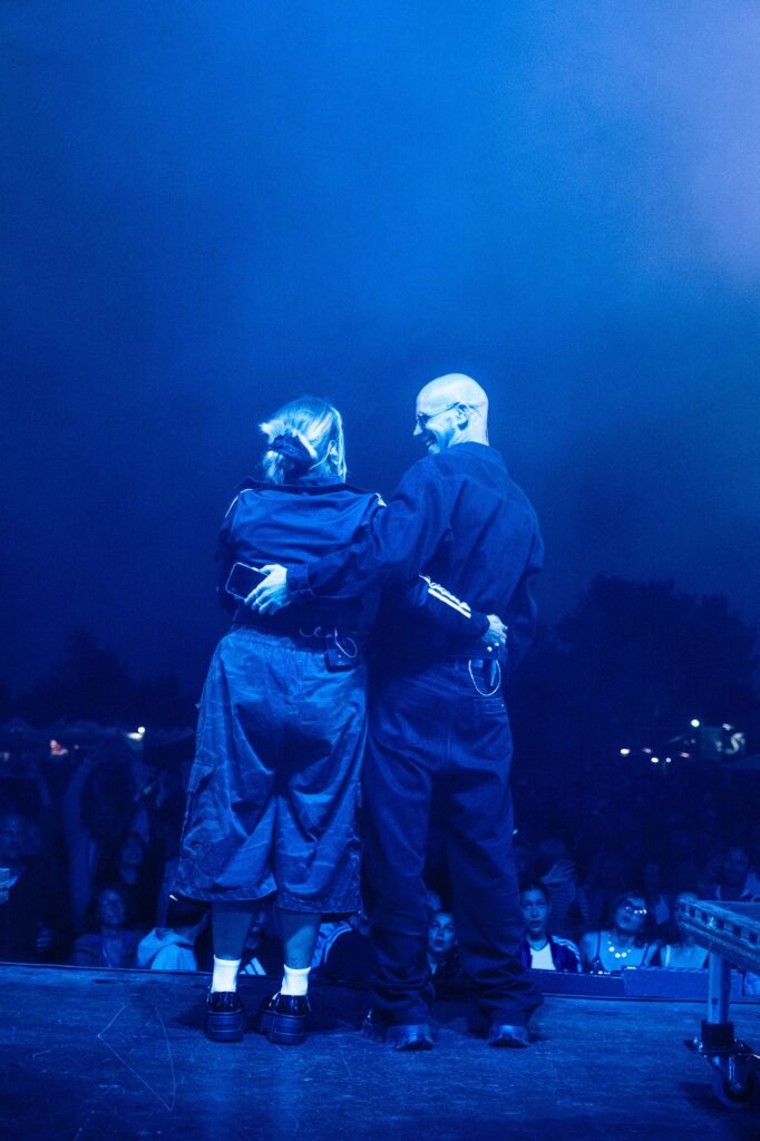 Baptiste et Tara de Jive Me enlacés, de dos, face au public d'un festival